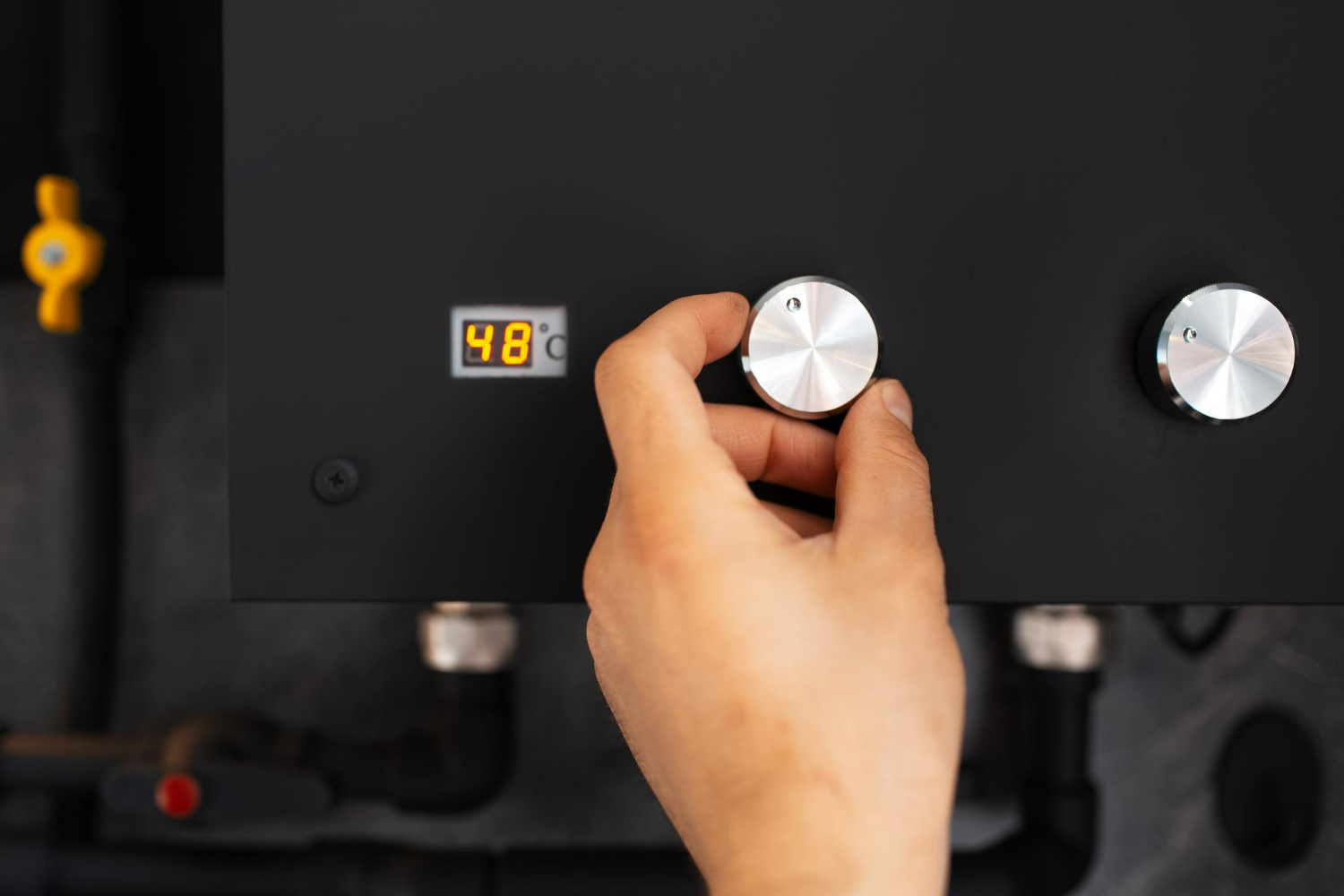 Closeup male hand adjusting temperature dial next to an LED digital display.