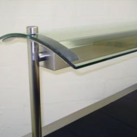 Close-up of curved glass sneeze guard mounted on stainless steel post